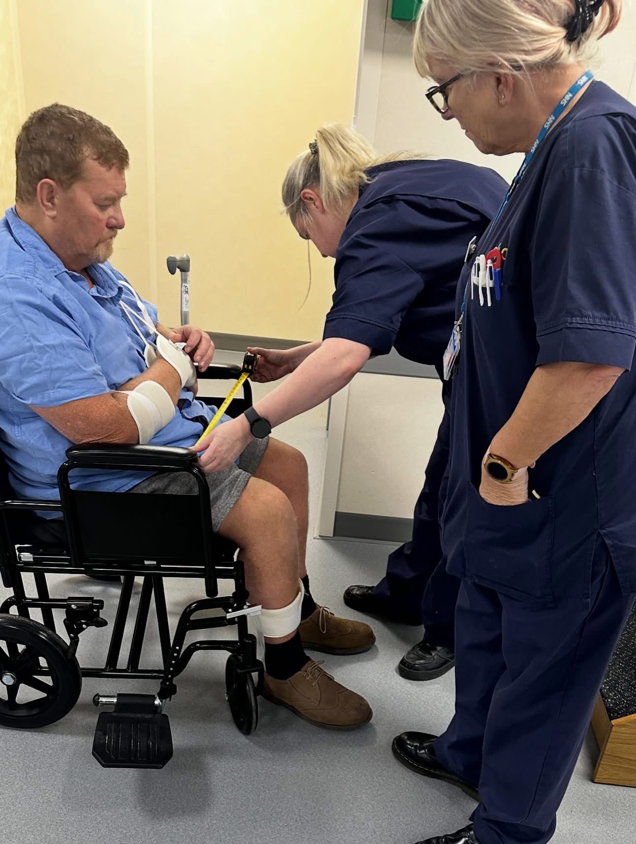 Andy seated in a wheelchair with hospital staff during his early recovery